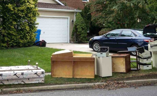 discarded wooden furniture and an old bed lined up by Baltimore, Maryland street curb waiting for trash pickup